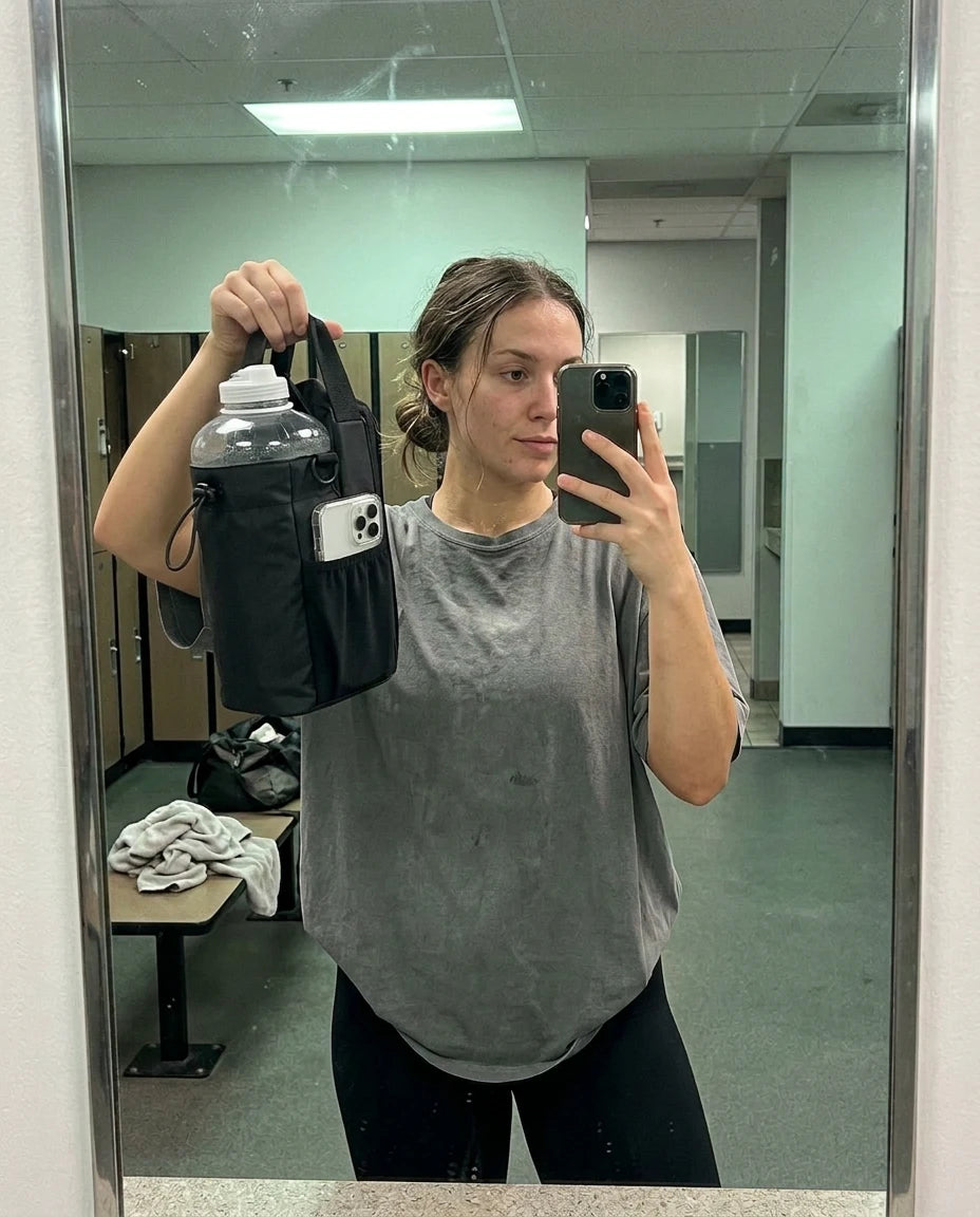 Frau hält die VEYNE Magnetic Gym Bag mit transparenter Flasche beim Spiegel-Selfie in der Umkleide